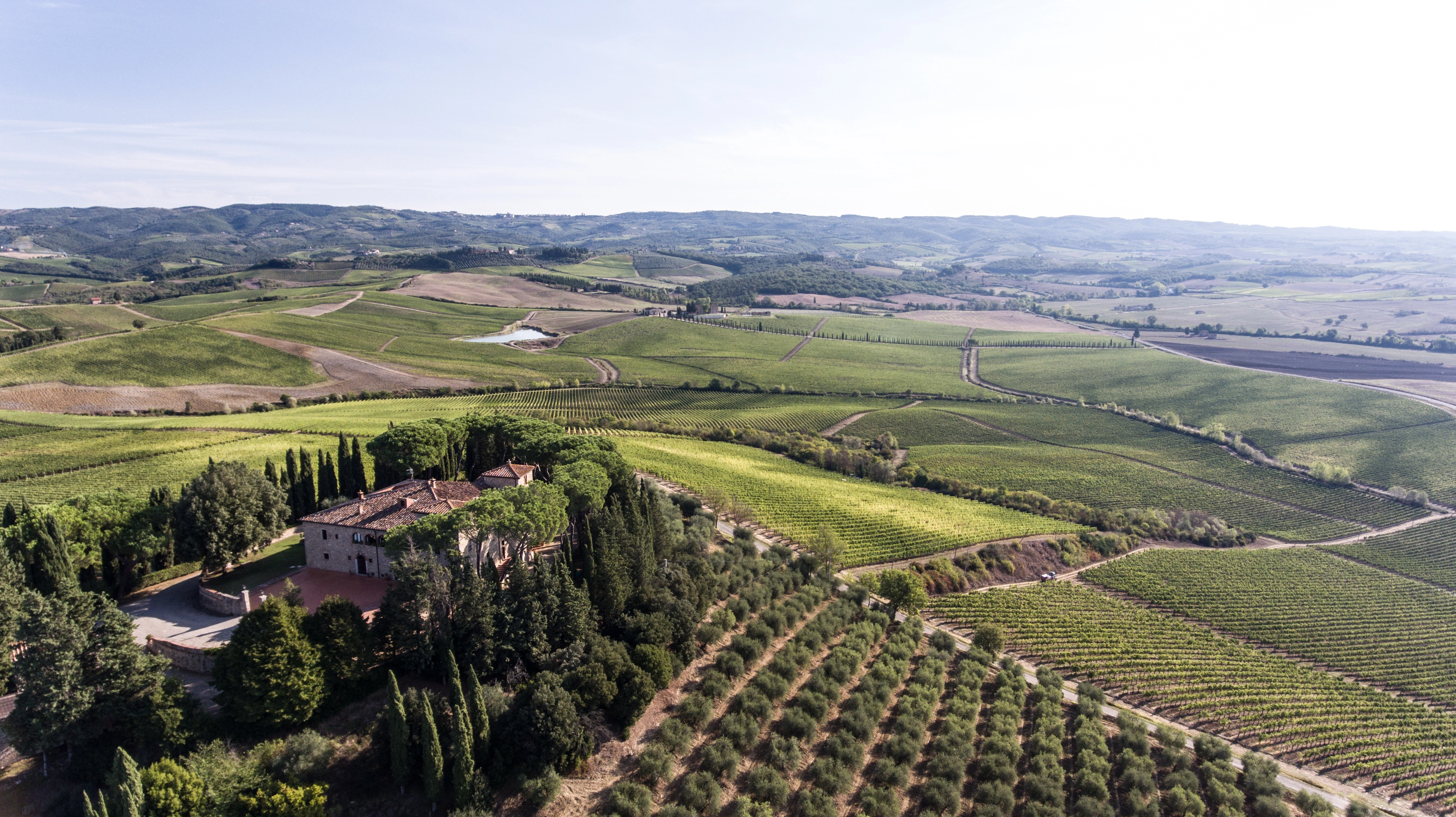 Luftaufnahme des Weinguts der Famiglia Cecchi auf einem Hügel in der Toskana mit umliegender Landschaft und sanften Weinbergen im Hintergrund