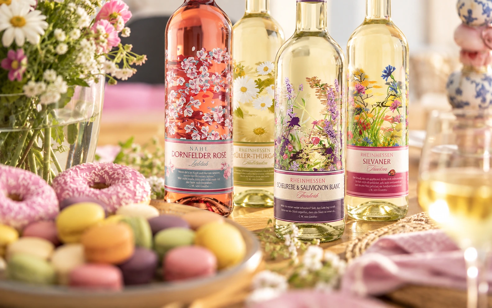 Moselland Weine mit floralem Design auf einem gedeckten Tisch mit Blumen und Gebäck