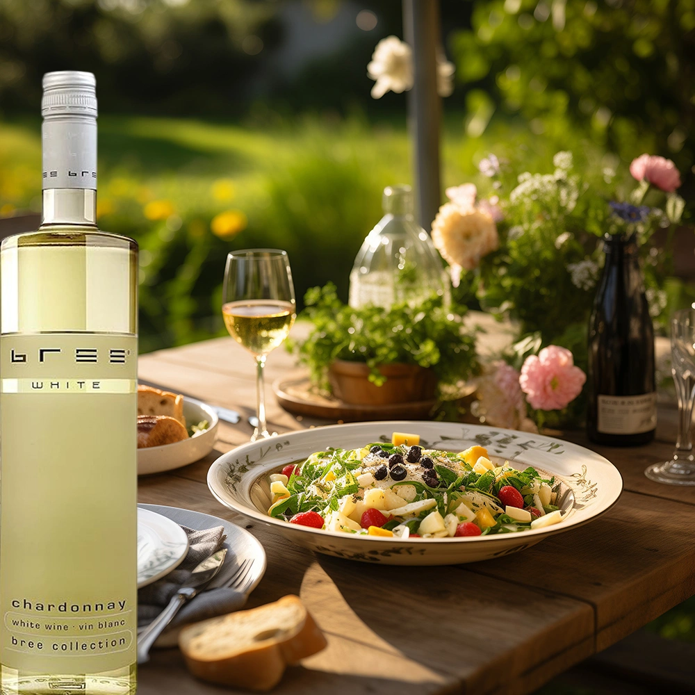 Bree Chardonnay Weinflasche auf einem gedeckten Tisch mit einem frischen Salat in einem sonnigen sommerlichen Garten als leichte und harmonische Weinbegleitung