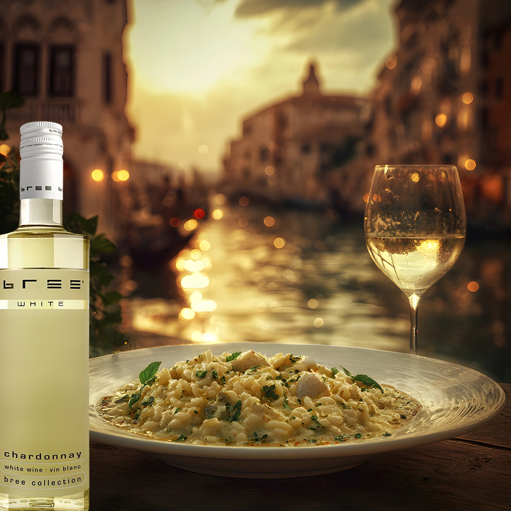 Kleine 0,25-Liter-Flasche Bree Chardonnay mit cremigem Risotto auf einem stimmungsvoll gedeckten Tisch in einer romantischen italienischen Gasse am Abend als elegante Weinbegleitung