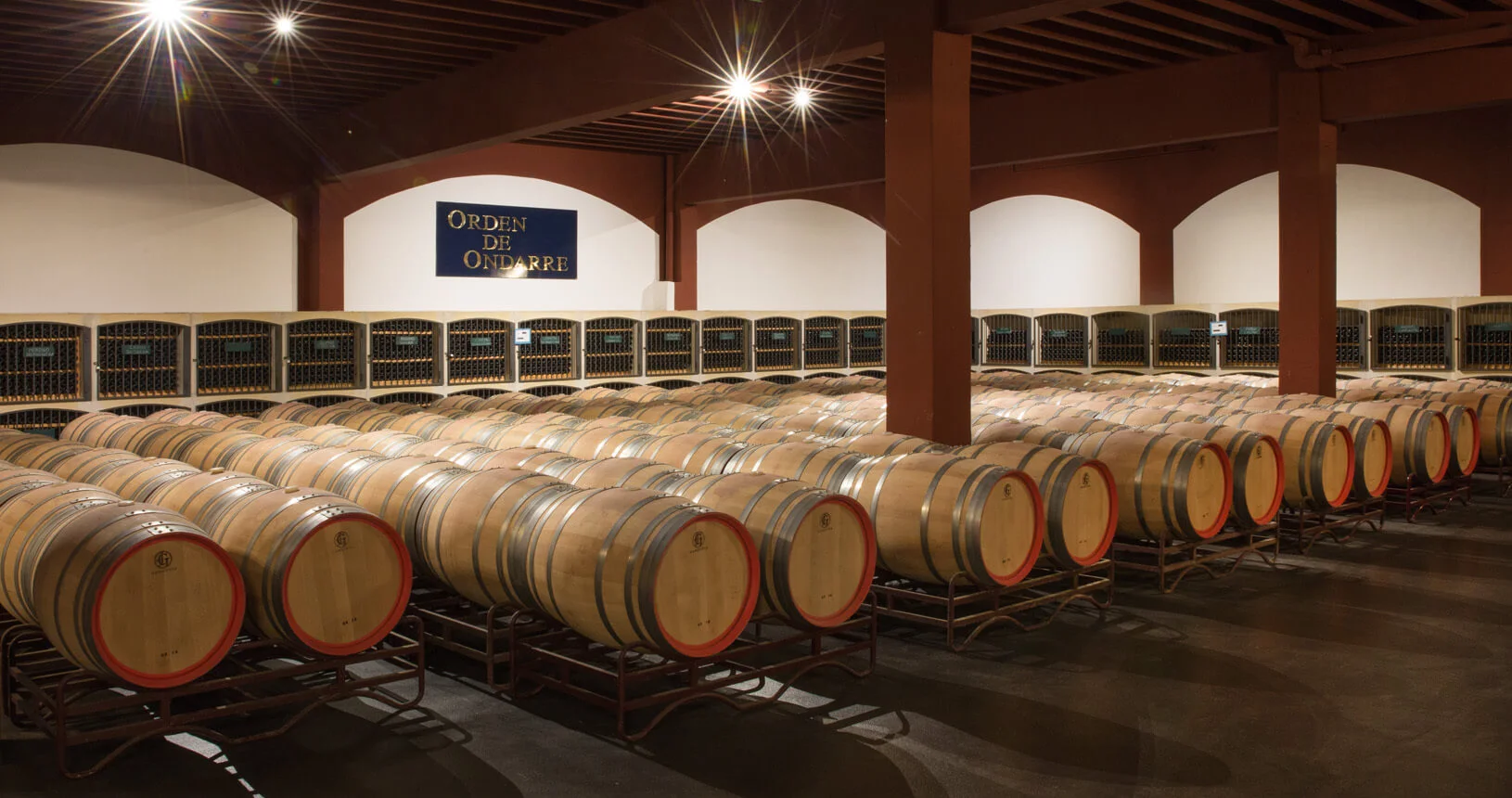 Weinkeller der Bodegas Ondarre mit ausgewählten Weinflaschen und Eichenfässern, Logo sichtbar