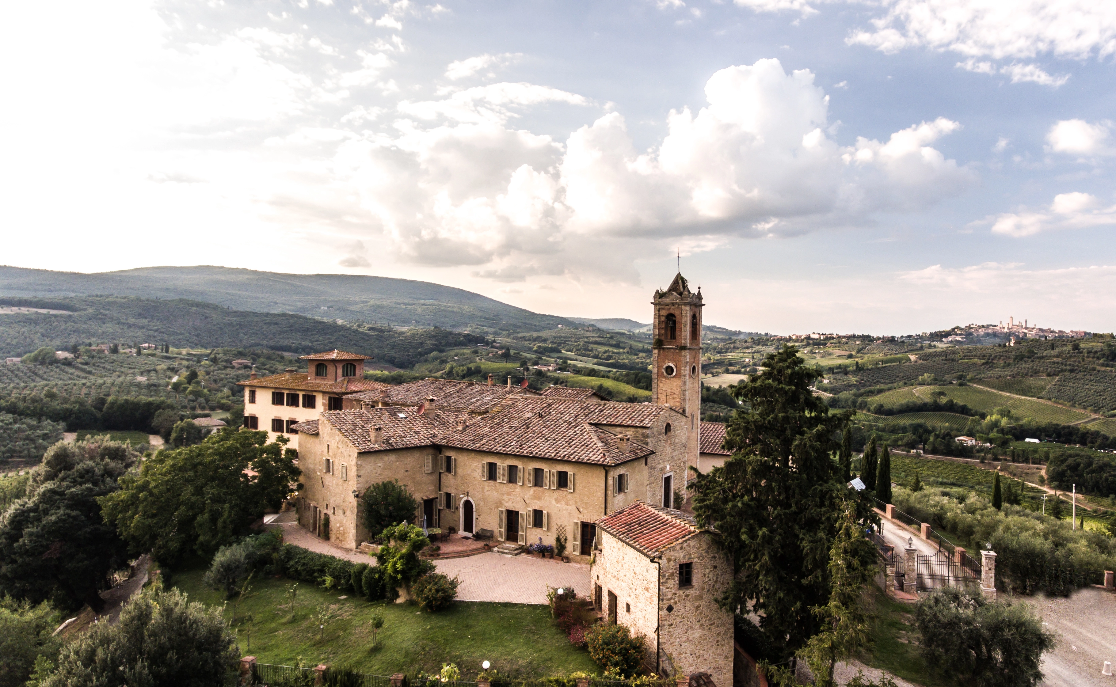 Villa Cerna Weingut auf einem zentral gelegenen Hügel in der Toskana, umgeben von weitläufigen Weinbergen und sanften Landschaften im Hintergrund unter warmem Licht.