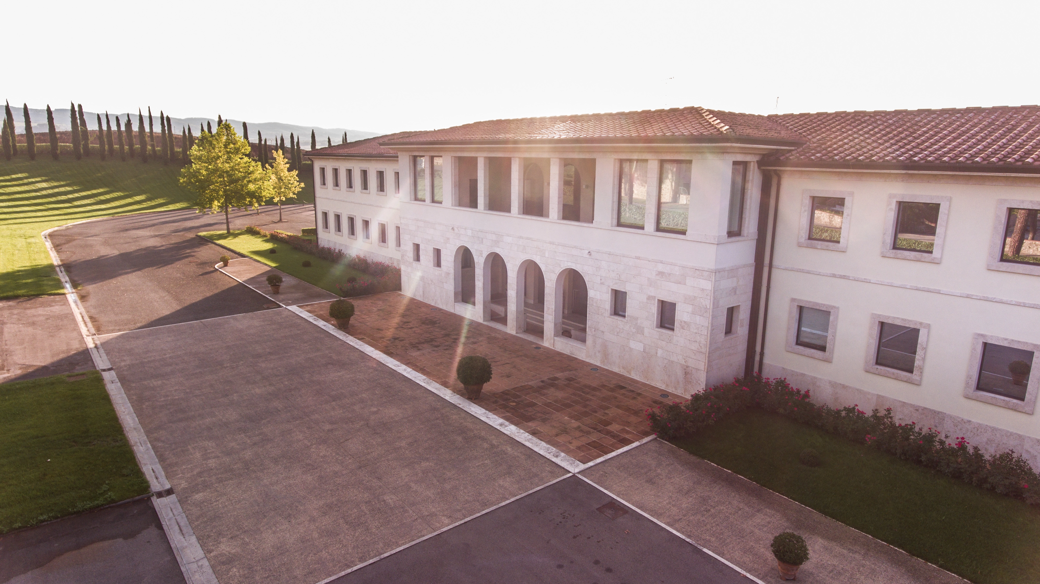 Weingutsgebäude der Famiglia Cecchi in der Toskana bei Sonnenuntergang, umgeben von Bäumen und hügeliger Landschaft in warmem Abendlicht