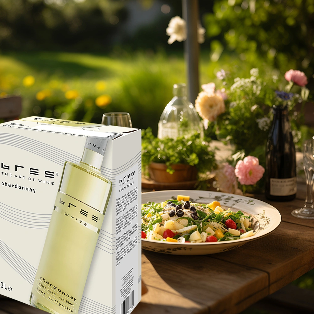 Bree Chardonnay 3,0 Liter Bag-in-Box auf einer sommerlich gedeckten Terrasse mit einem frisch zubereiteten Salatteller und entspannter Atmosphäre als leichte Weinbegleitung