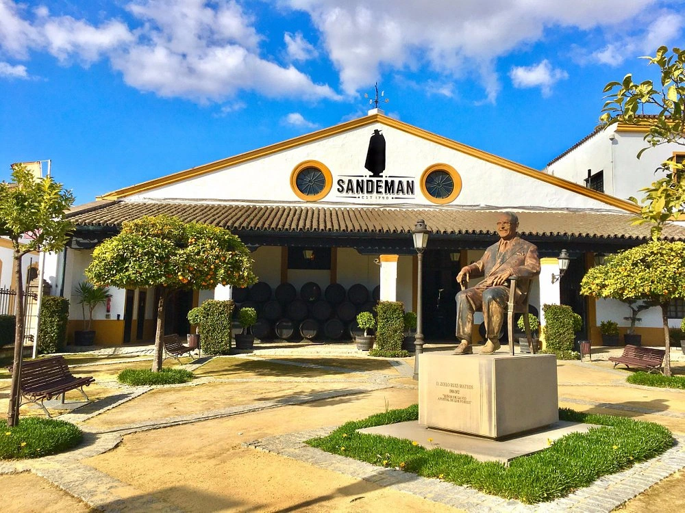 Sandeman Gebäude mit der Statue von George Sandeman auf dem Vorplatz unter blauem Himmel in Vila Nova de Gaia