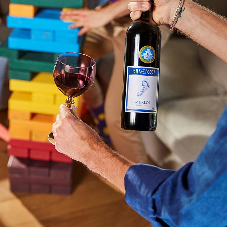 Barefoot Merlot Flasche mit gefülltem Weinglas vor bunten Bauklötzen arrangiert