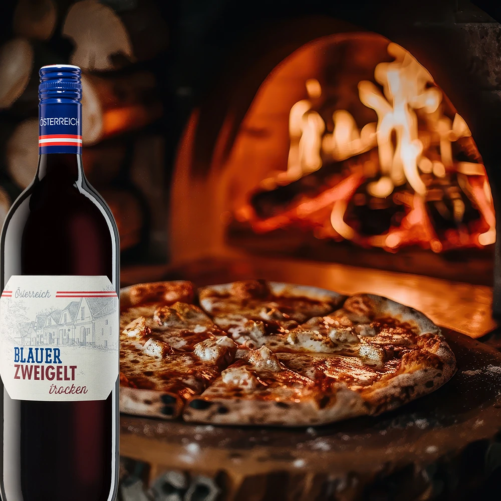Aichenberg Blauer Zweigelt Rotwein mit Pizza auf gedecktem Tisch vor Kaminfeuer