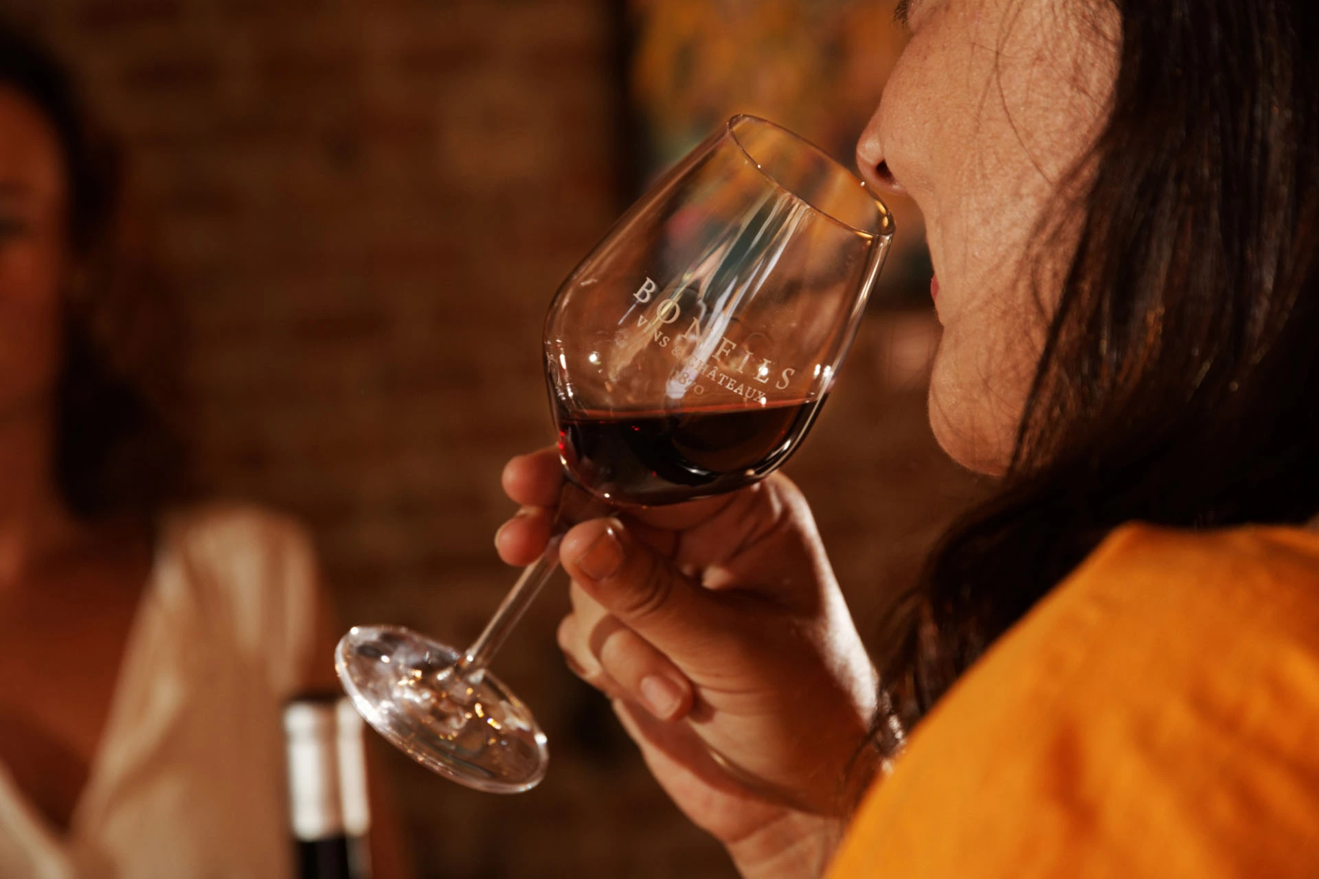 Frau hält ein Weinglas mit Bonfils Rotwein und riecht am Bukett des Weins