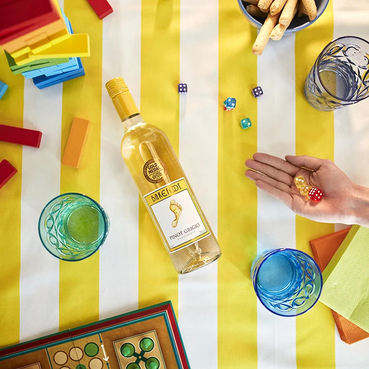 Barefoot Pinot Grigio liegend auf einer Picknickdecke mit Getränken, Snacks und Gesellschaftsspielen