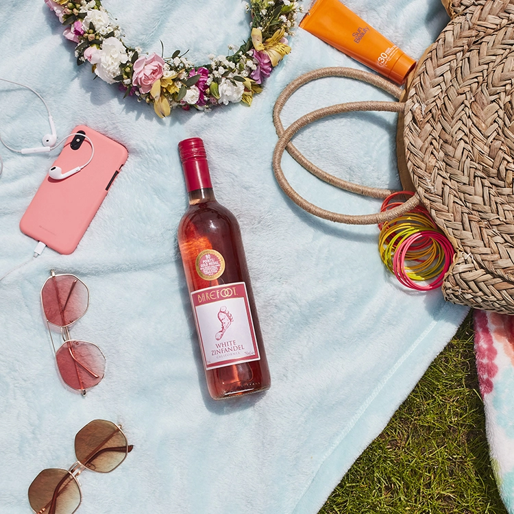 Barefoot White Zinfandel Flasche auf einer Picknickdecke im sonnigen Gras