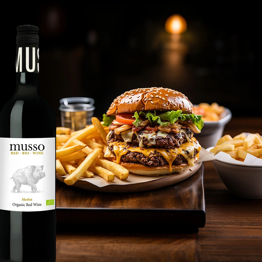 Musso Merlot Bio Rotwein mit Hamburger und Pommes auf rustikaler Holzplatte angerichtet