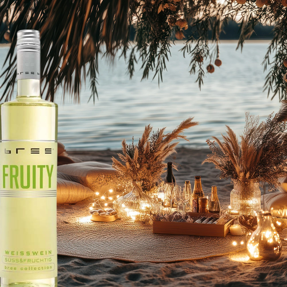 Bree Fruity Weiß Weinflasche auf einer gemütlichen Picknickdecke am Strand mit warmem Kerzenlicht und entspannter Abendstimmung als fruchtige Weinbegleitung