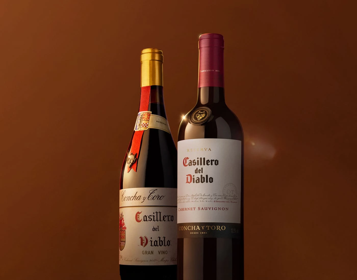 Zwei Casillero del Diablo Weinflaschen stehen einzeln vor einem Hintergrund und wurden leicht von unten fotografiert