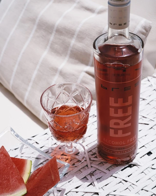 Bree Rosé alkoholfrei mit einem Glas Rosé und Wassermelone auf einer Picknickdecke in sommerlicher Outdoor-Atmosphäre