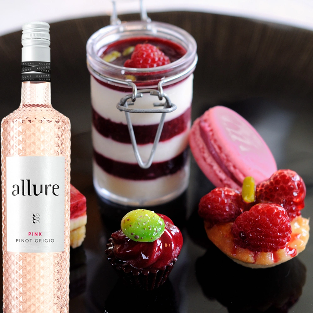 Flasche Allure Pinot Grigio Pink neben einem Teller mit Süßspeisen und frischen Früchten, stilvoll angerichtet