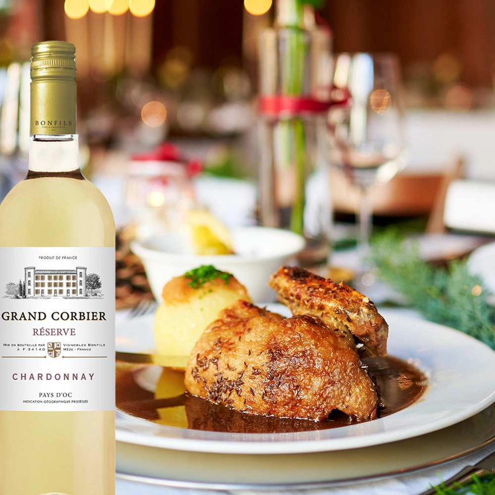 Bonfils Grand Corbier Réserve Chardonnay mit Geflügel in dunkler Soße auf elegantem Festtagstisch, stilvolle Genussmomente bei warmer Beleuchtung