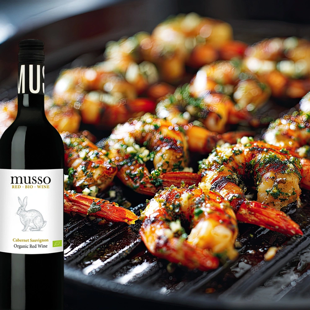 Musso Cabernet Sauvignon Bio Rotwein mit gegrillten Scampis auf mediterran angerichtetem Teller in stilvoller Atmosphäre