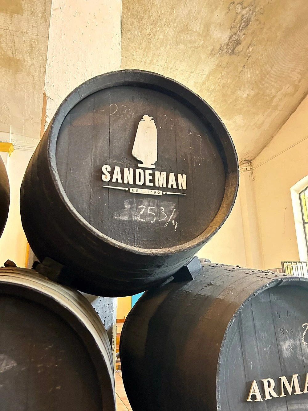 Gestapelte Sandeman Fässer mit dem ikonischen Don-Logo in einem traditionellen Weinkeller
