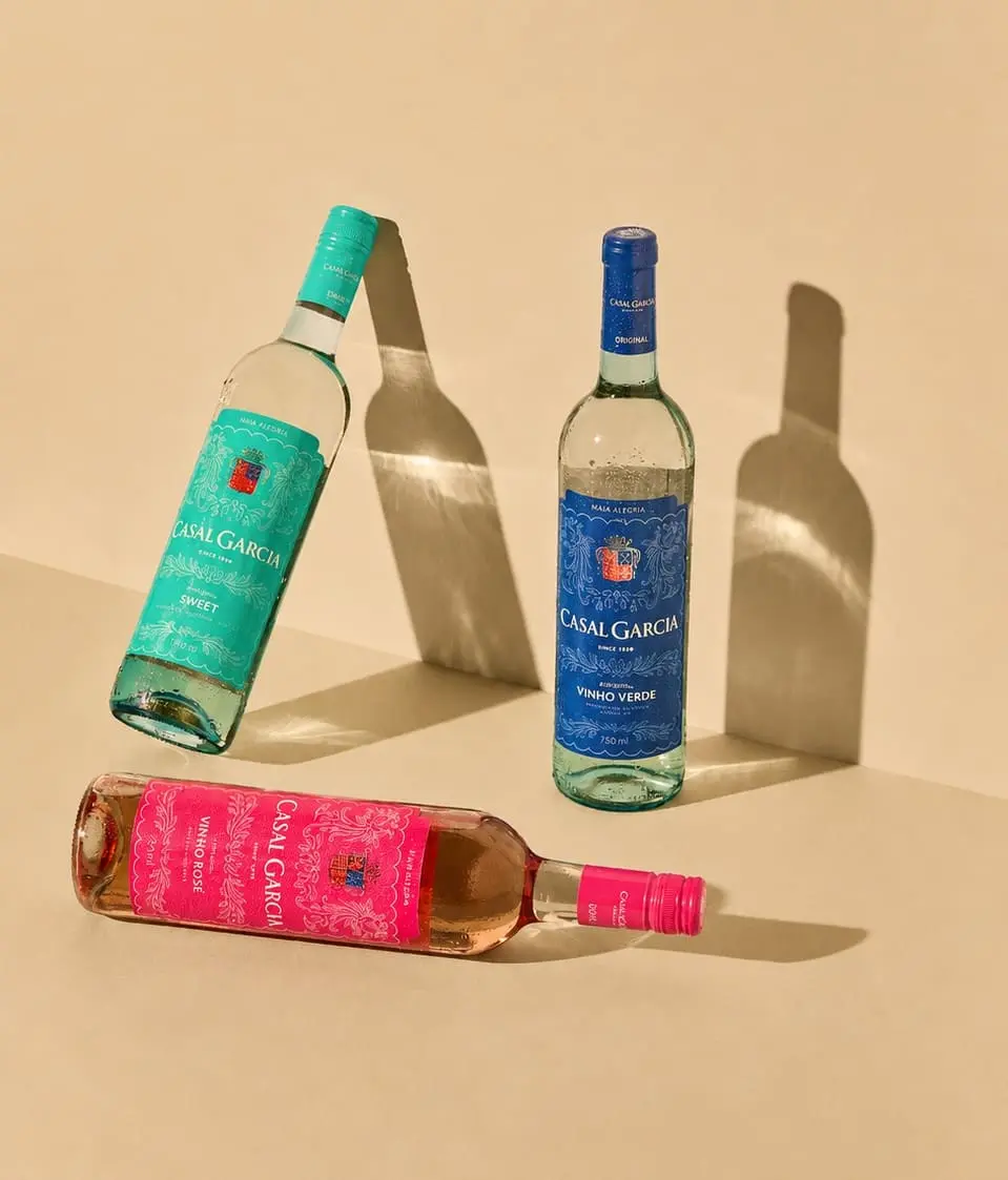 Casal Garcia Vinho Verde, Vinho Rosé und Sweet gemeinsam liegend und stehend als Ensemble vor beiger Wand mit natürlichem Sonnen- und Schattenspiel