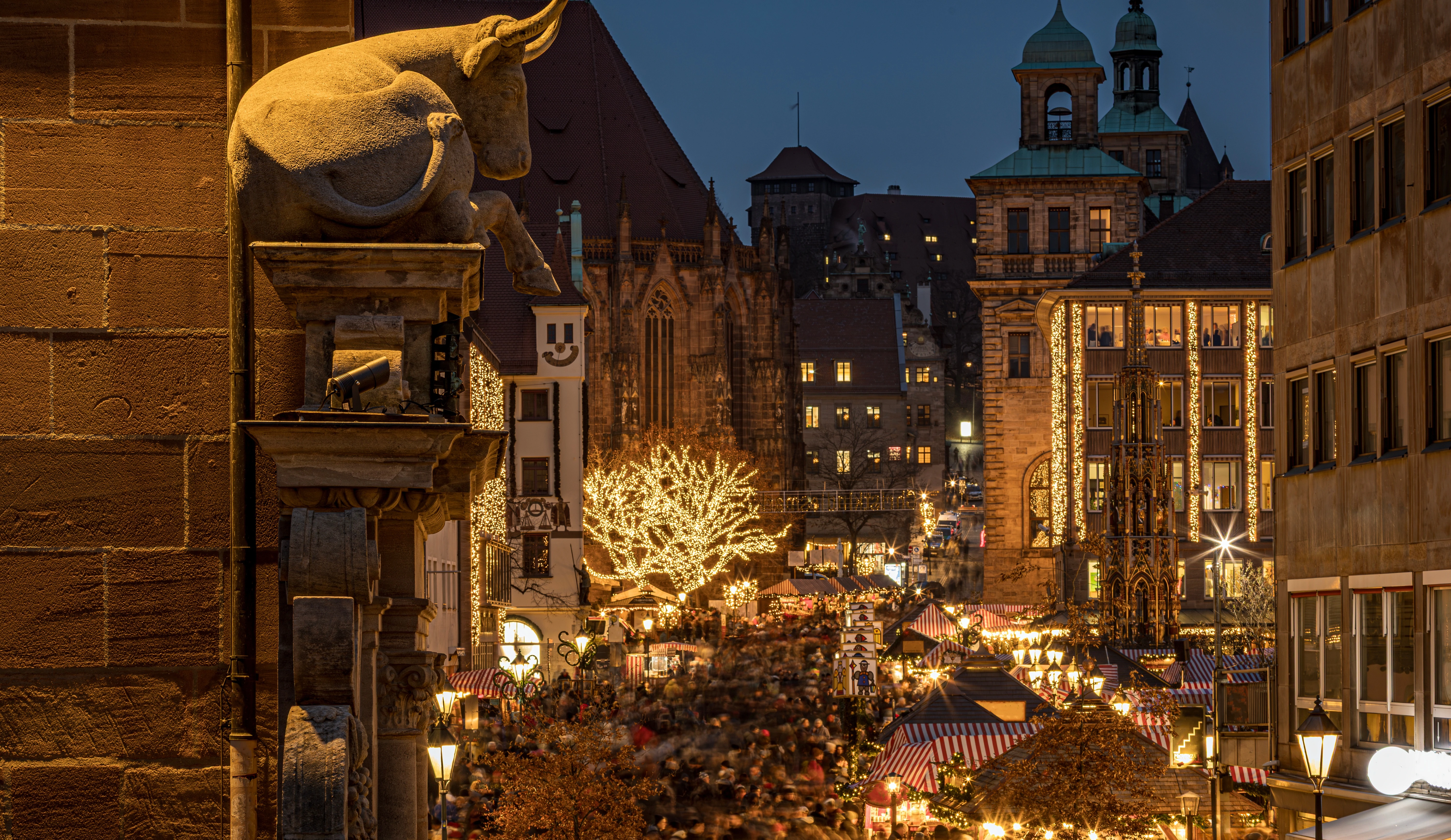 Vogelperspektive über den Nürnberger Christkindlesmarkt in der Abenddämmerung mit festlich beleuchteten Marktständen, historischen Häusern und der Frauenkirche im Hintergrund - die Heimat des Sternthaler Nürnberger Christkindles Glühweins.