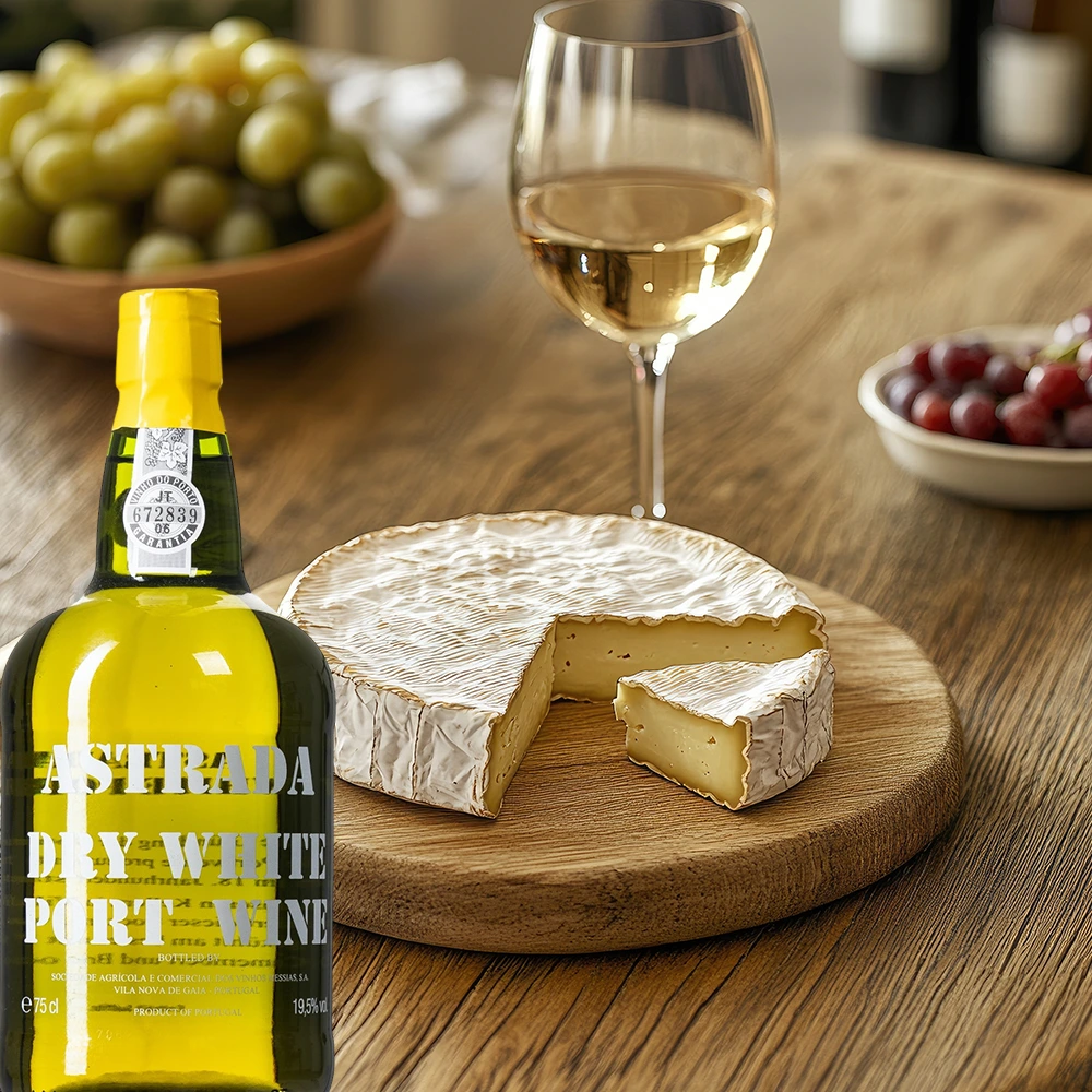 Flasche Astrada Dry White Port neben einer Käseplatte mit Camembert und Weintrauben auf einem gedeckten Tisch arrangiert