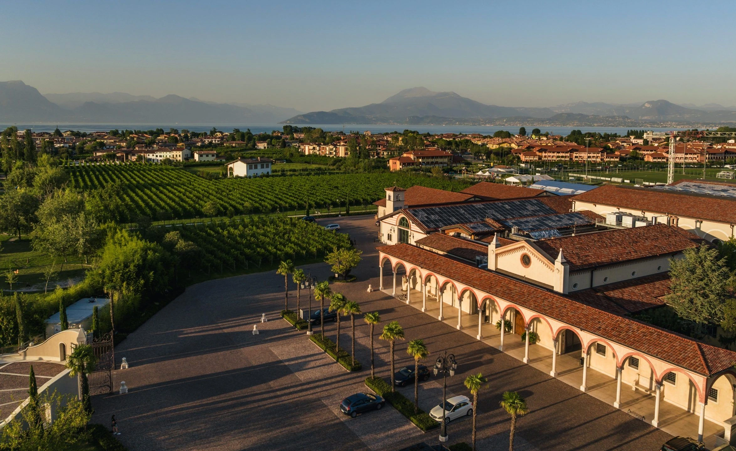 Vogelperspektive auf das Weingut Cà dei Frati bei untergehender Sonne mit Blick auf den Gardasee und die umliegenden Berge im Hintergrund