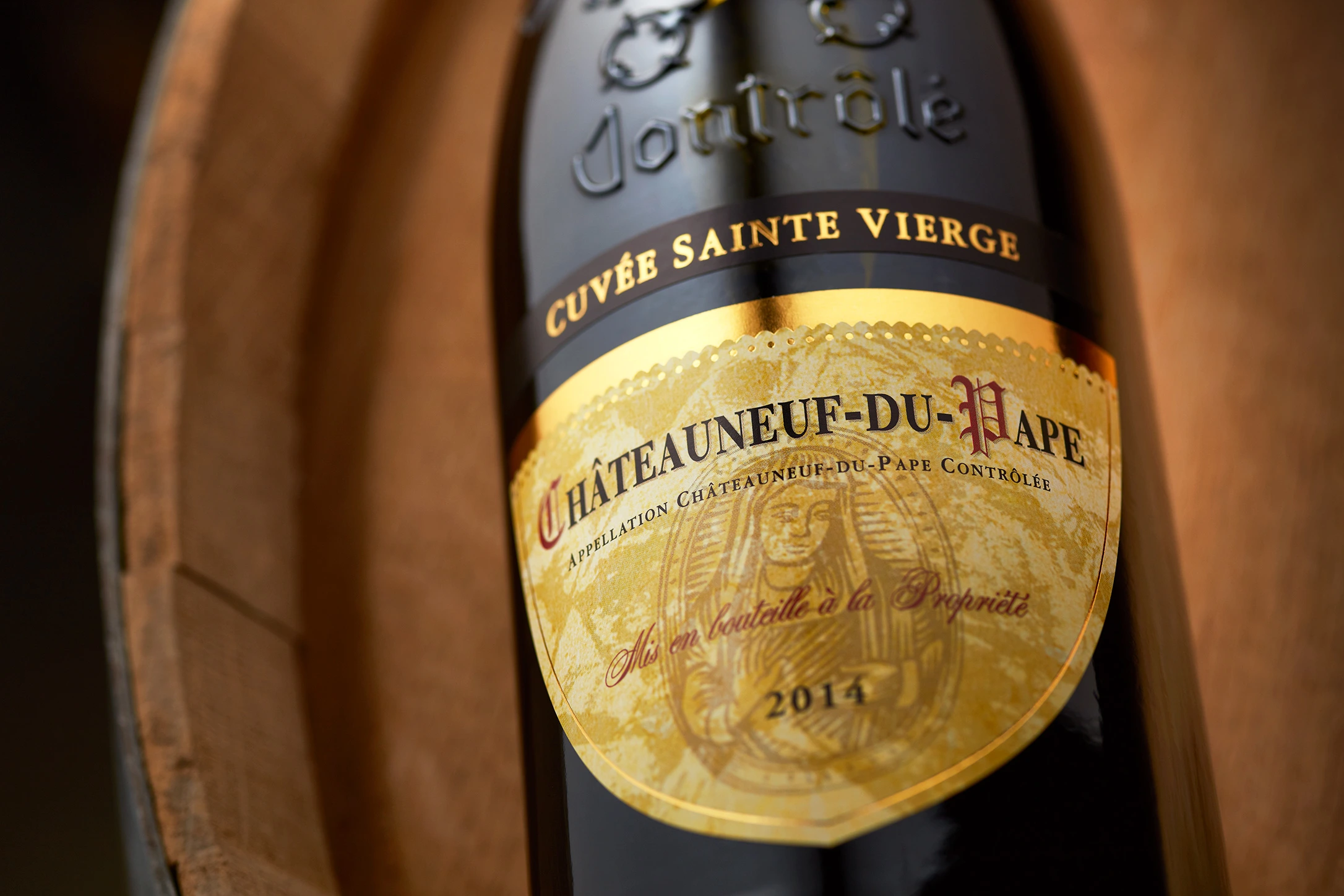 Flasche Sainte Vierge Châteauneuf-du-Pape auf einem traditionellen Holzfass im Weinkeller