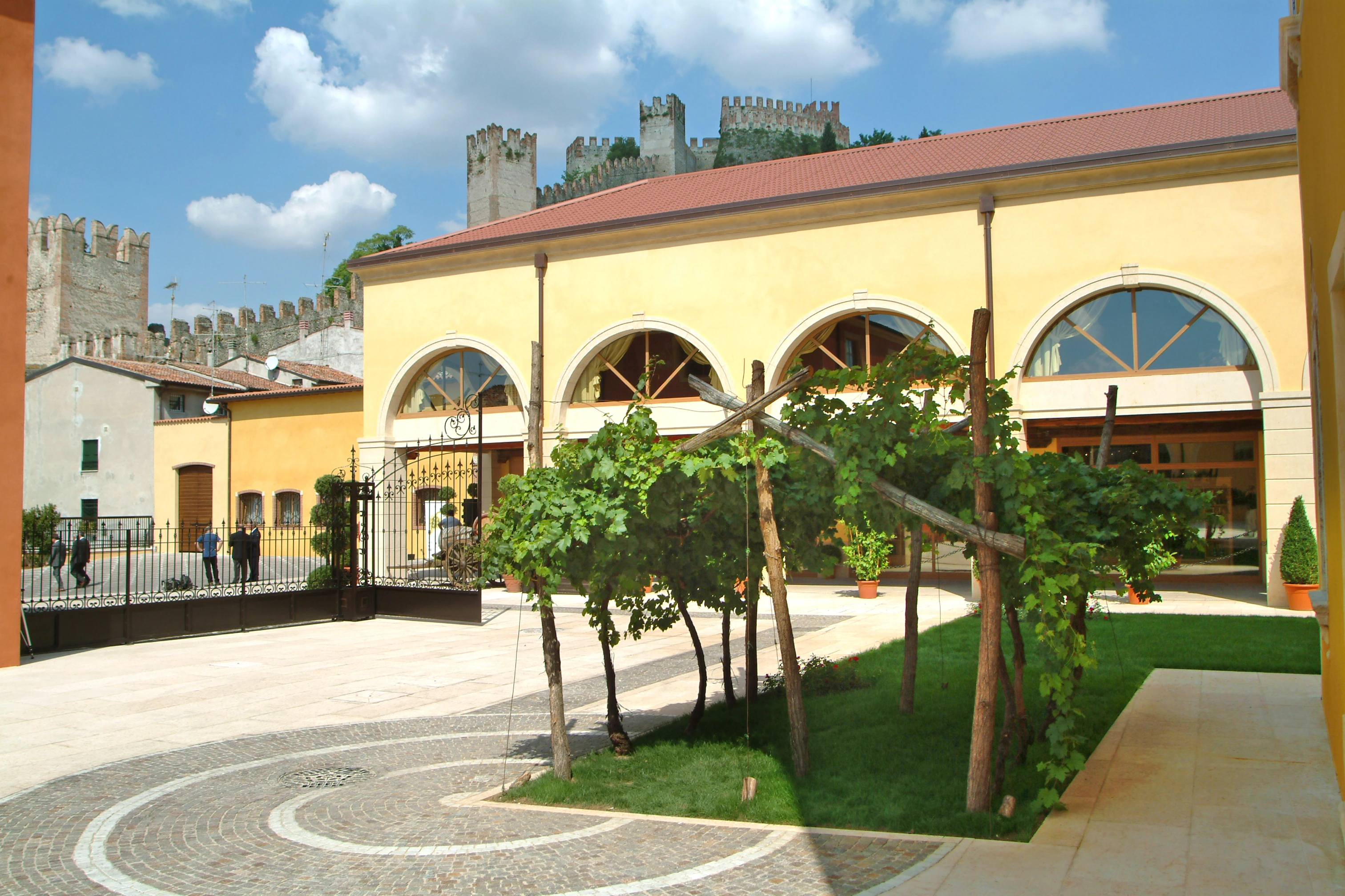 Innenhof der Kellerei der Cantina di Soave mit Blick auf die historische Burg Castello Scaligero, die auf einem Hügel im Hintergrund über der Landschaft thront