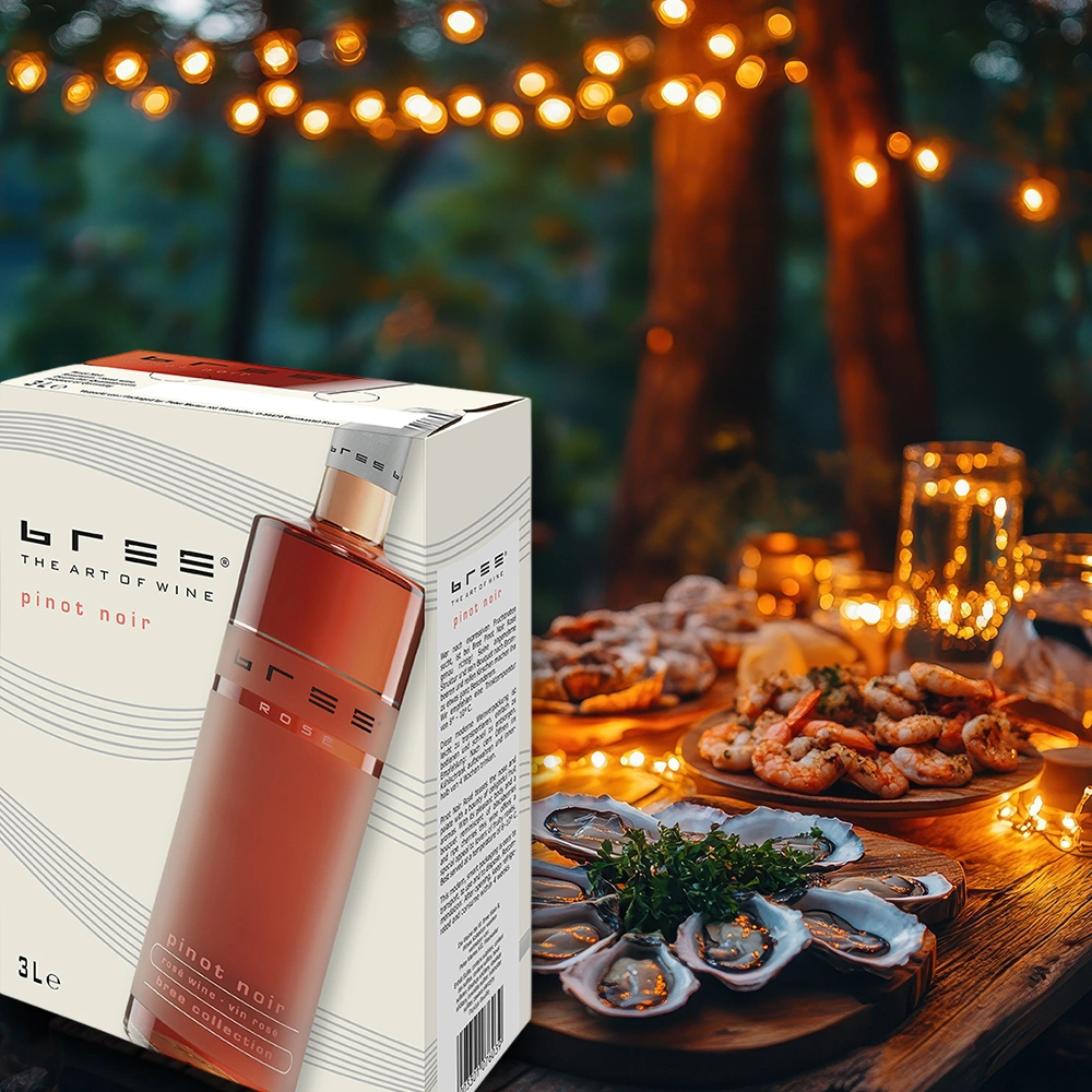 Bree Pinot Noir 3,0 Liter Bag-in-Box auf einer stimmungsvoll gedeckten Terrasse am Abend mit frischen Austern, Meeresfrüchten und sommerlicher Beleuchtung als stilvolle Weinbegleitung